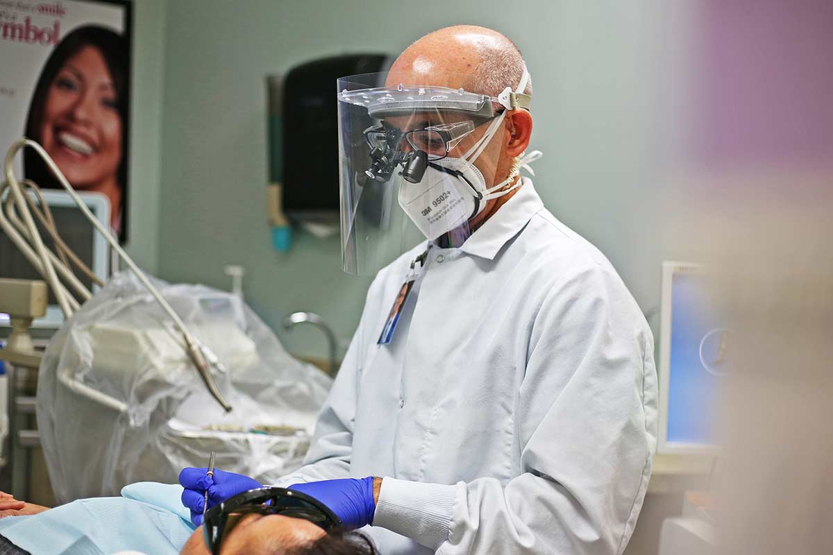 Dr. Michael Bass performs a routine dental hygiene exam while wearing the AerFrame over his face mask.