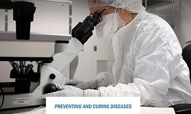 researcher looking through microscope